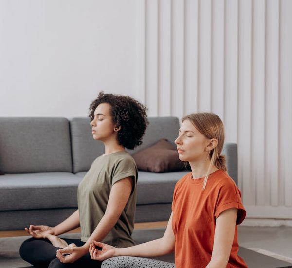 Woman in a calm yoga pose in a minimalist room with soft light.